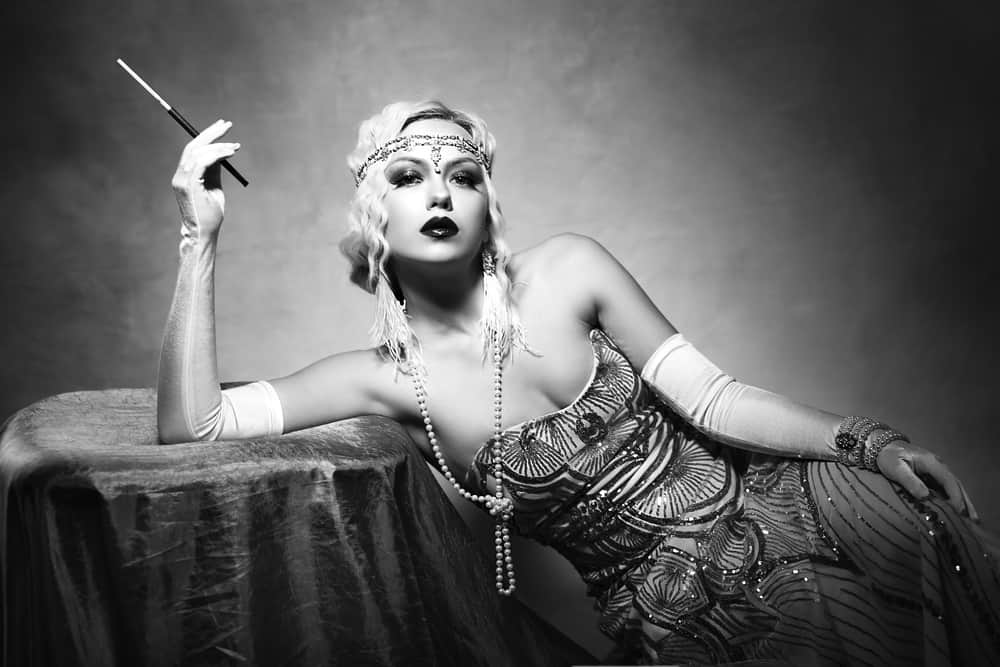 a woman dressed in retro flapper style fashion and holding a cigarette