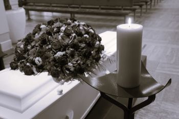 a white casket with flowers on top and a candle beside it