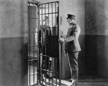 Policeman opening the door of a jail cell with prisoner inside