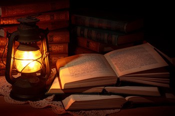old oil lamp with stacks of books beside it